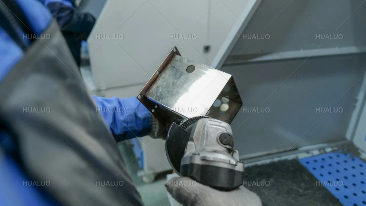 A worker grinding and smoothing the edges of a metal equipment part.